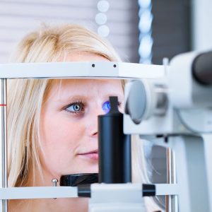 12115911 - optometry concept - pretty, young female patient having her eyes examined by an eye doctor (color toned image; shallow dof)